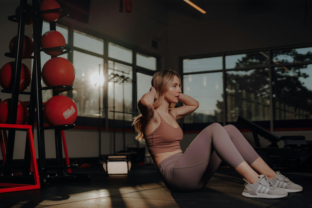 Confident woman doing sit-ups at the gym in stylish activewear.