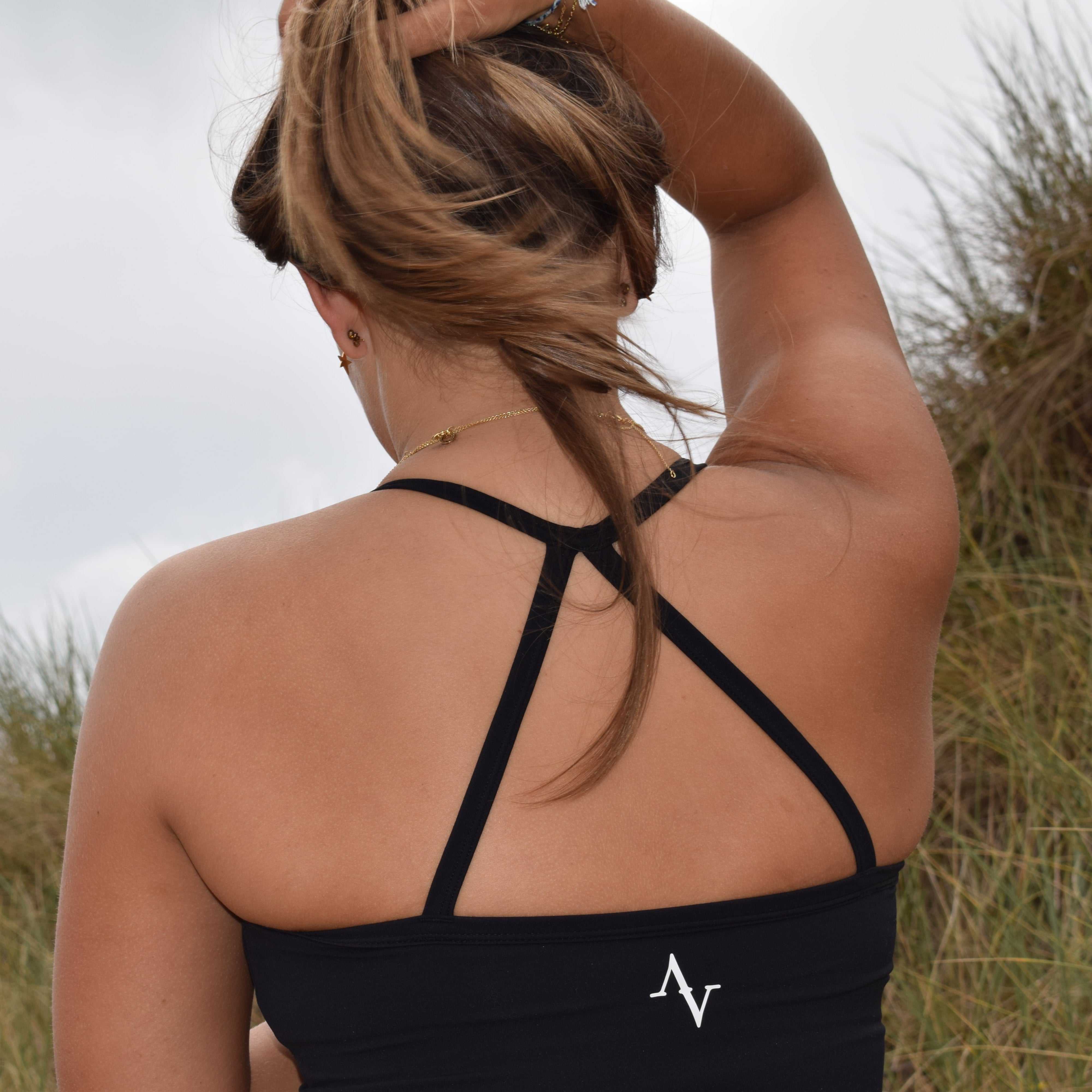 Ivya Seamless Spaghetti Top in black with crisscross back straps, made from NaiFlex fabric for a comfort fit. Ideal activewear for outdoor workouts.