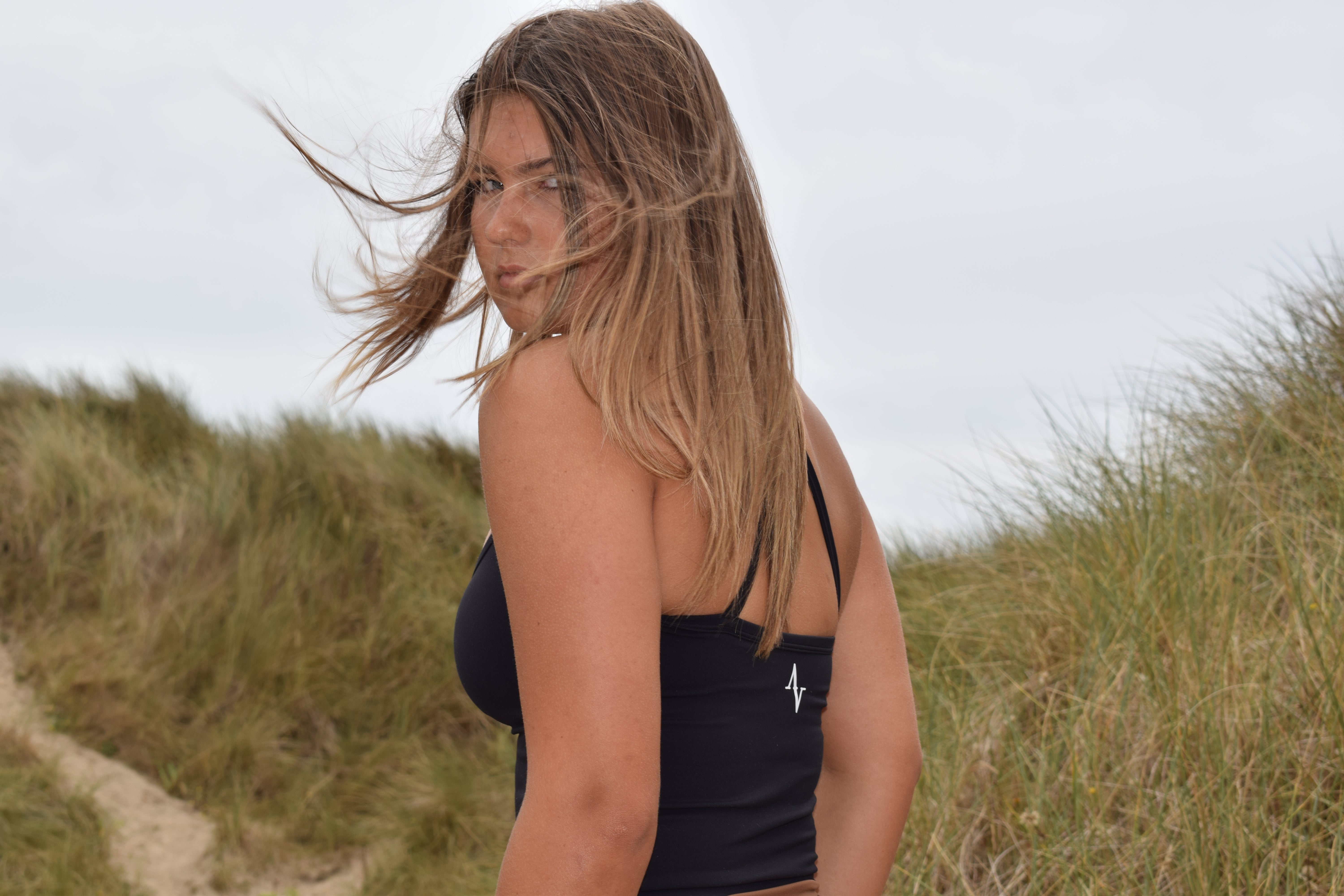 Ivya Seamless Spaghetti Top in black NaiFlex fabric worn outdoors, showcasing comfort fit and sleek design for activewear style.